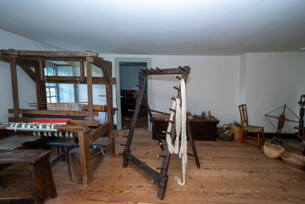 Historical Spinning & Weaving Room at Stratford Hall with spinning wheels, looms, and woven textiles.